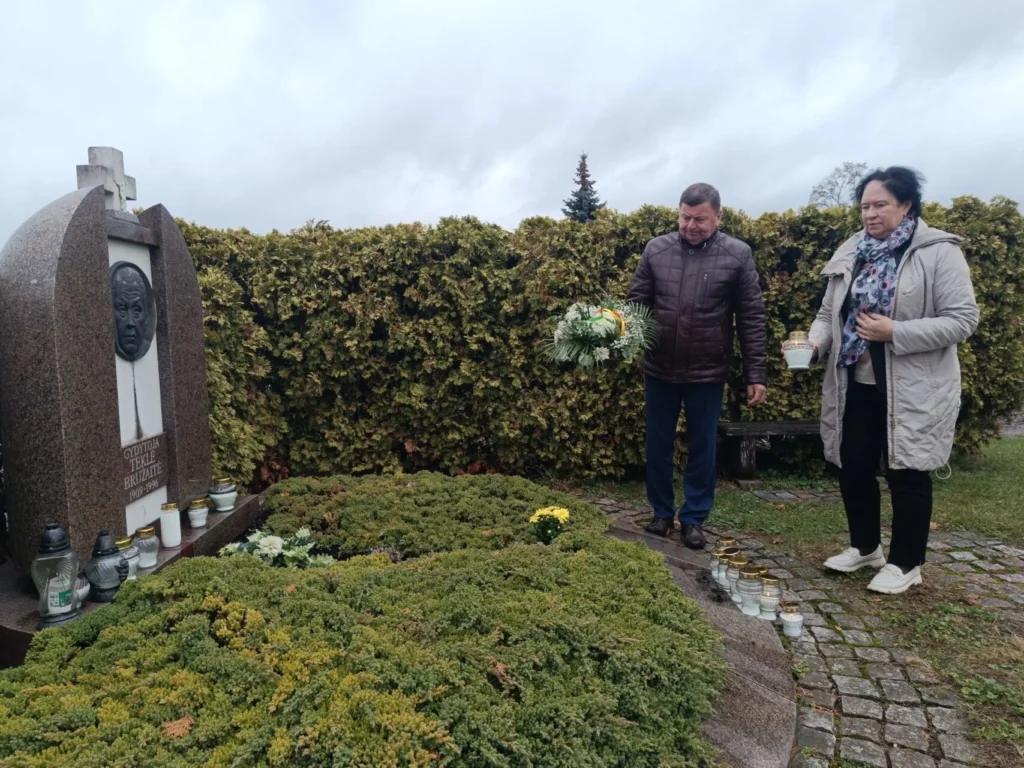 Pilką dieną, pora pagarbiai stovi prie didelio, žole apaugusio Teklės Bruzaitės kapo su įspūdingu metaliniu biustu ant antkapio.