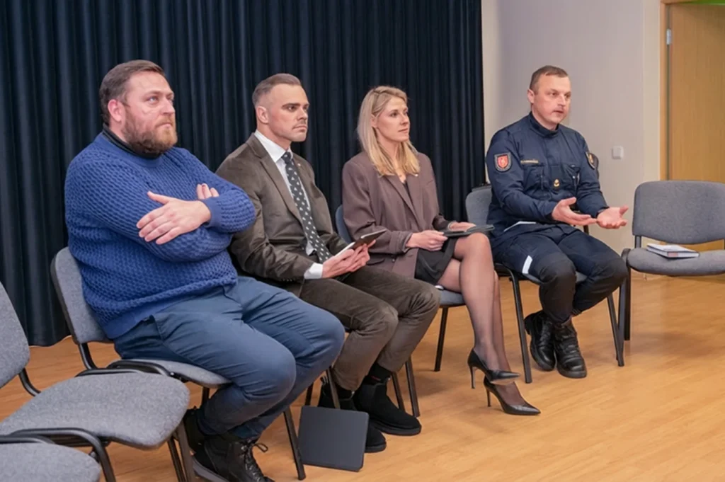 Susikaupę keturi panelės nariai, įskaitant pareigūną, sėdi aptardami svarbius klausimus.