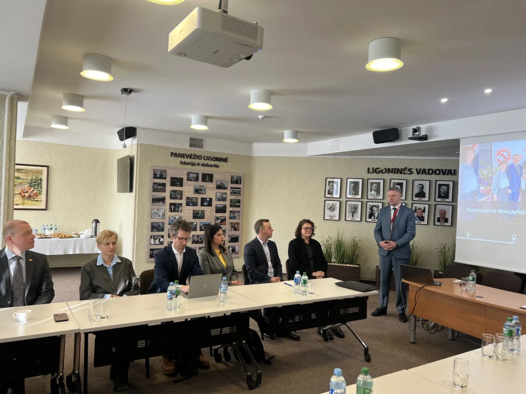 Panevėžio ligoninės konferencijos dalyviai klausosi pranešėjo prie stalo.