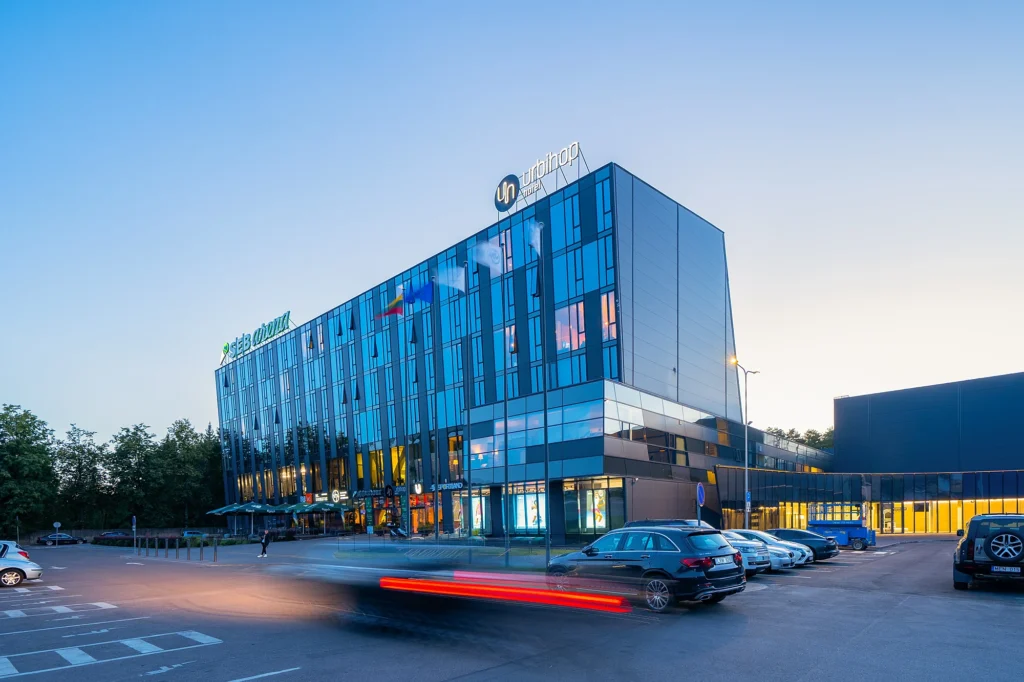 Modernus „SEB arenos“ ir „Urbihop“ viešbučio pastatas vakariniu metu.
