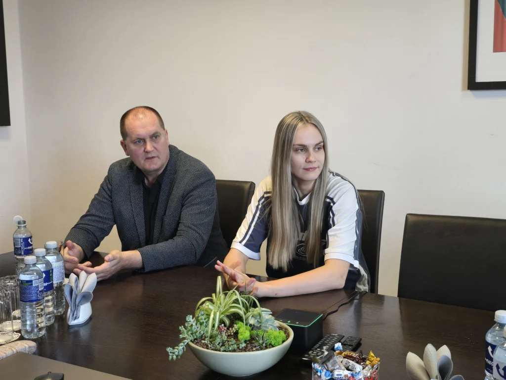 Vyras ir sportinę aprangą dėvinti mergina sėdi susitikime
