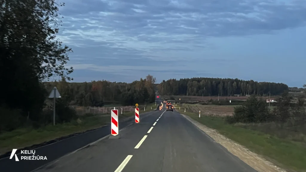 Asfaltuotas kelias su įspėjamaisiais ženklais apie vykdomus darbus.