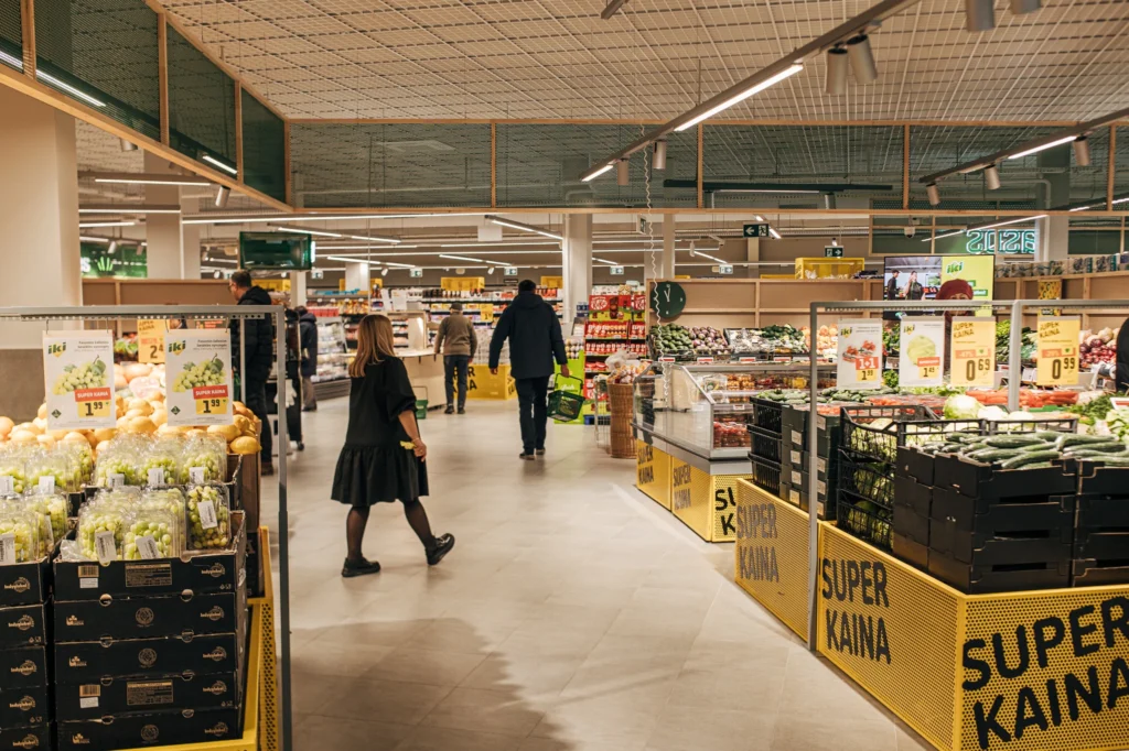 Žmonės apsiperka prekybos centro vaisių ir daržovių skyriuje.