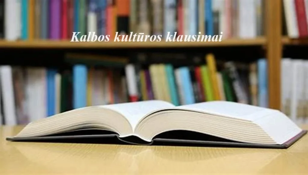Atversta stora knyga ant medinio stalo, fone – neryškios bibliotekos lentynos ir baltas užrašas.