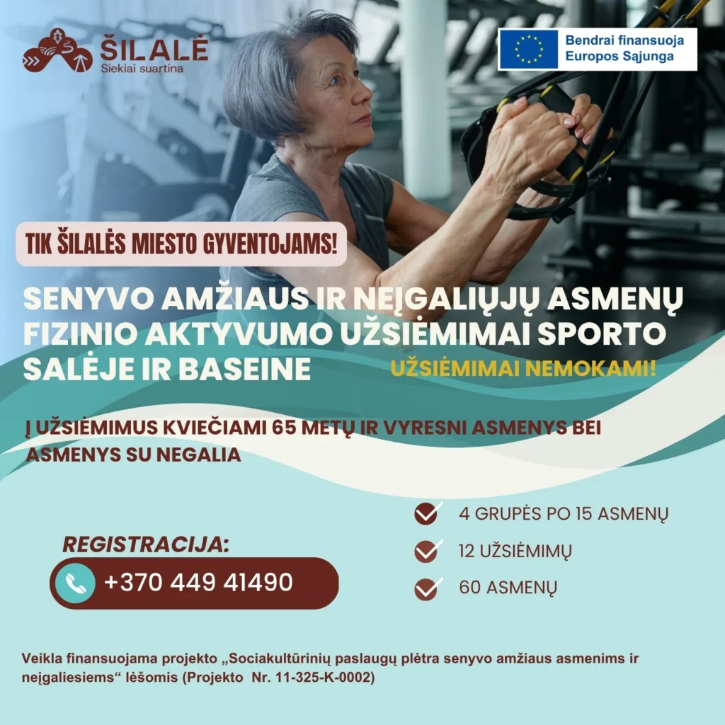 Vyresnio amžiaus moteris sporto salėje susikaupusi atlieka pratimus laikydamasi už pakabinamų treniruoklių rankenų.