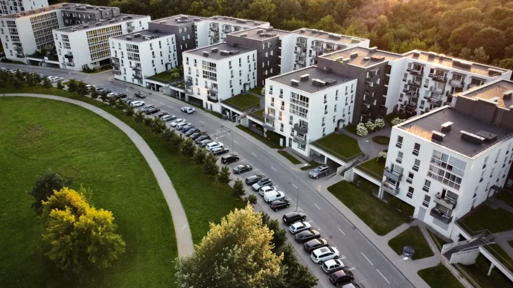Modernus daugiabučių namų kvartalas iš paukščio skrydžio su sutvarkyta aplinka ir automobilių stovėjimo aikštele.