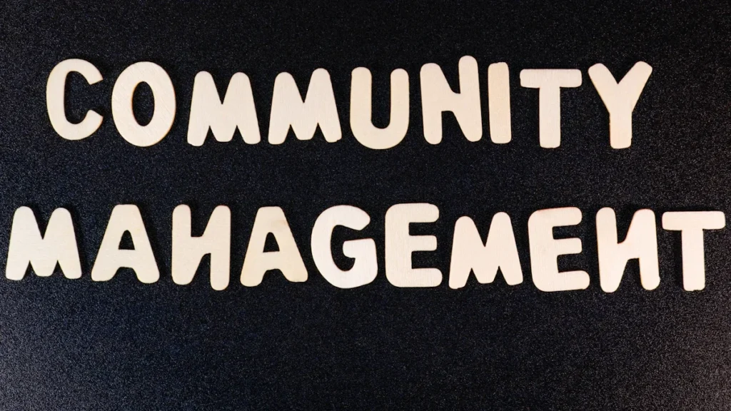 Medinės raidės ant tamsaus fono, sudarančios užrašą „Community Management“, simbolizuojantį bendruomenės įsitraukimą.