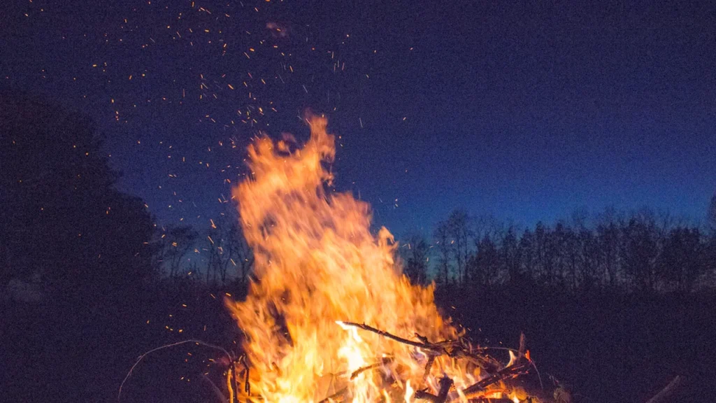 Didelis laužas tamsiame fone, simbolizuojantis vasaros saulėgrįžos ir Joninių tradicijas Lietuvoje.