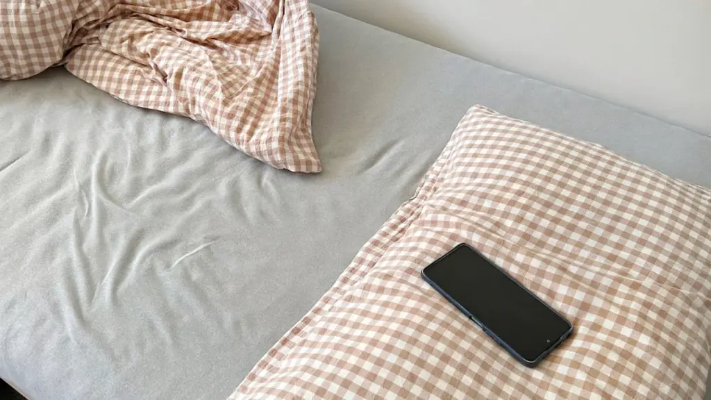Išmanusis telefonas guli ant lovos šalia pagalvės prieš miegą vakare.
