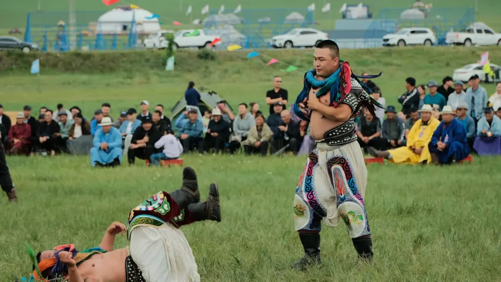 Tradicinių imtynių varžybos atvirame lauke per kultūros festivalį su žiūrovais fone.