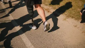 Bėgikas su kojos protezu sportuoja lauke bėgimo takelyje saulėtą dieną.