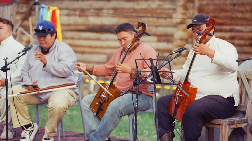 Liaudiškos muzikos grupė atlieka kūrinius lauko scenoje su tradiciniais styginiais instrumentais.