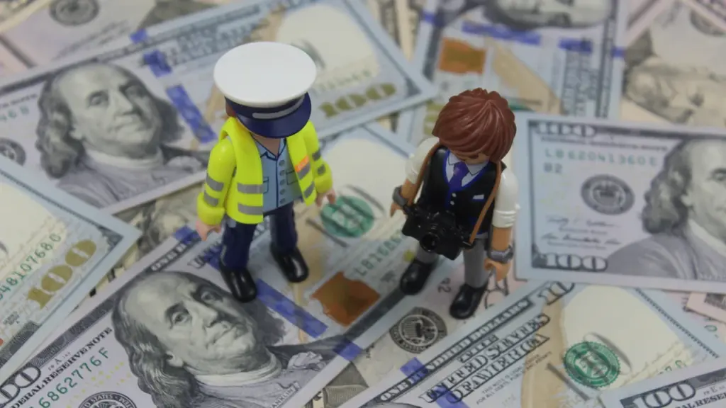 Žaislinės figūrėlės stovi ant krūvos JAV dolerių banknotų simbolizuojančios finansinį susitarimą.