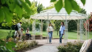 Jaunuoliai leidžia laiką žaliame parke prie balto ažūrinio paviljono saulėtą vasaros dieną.