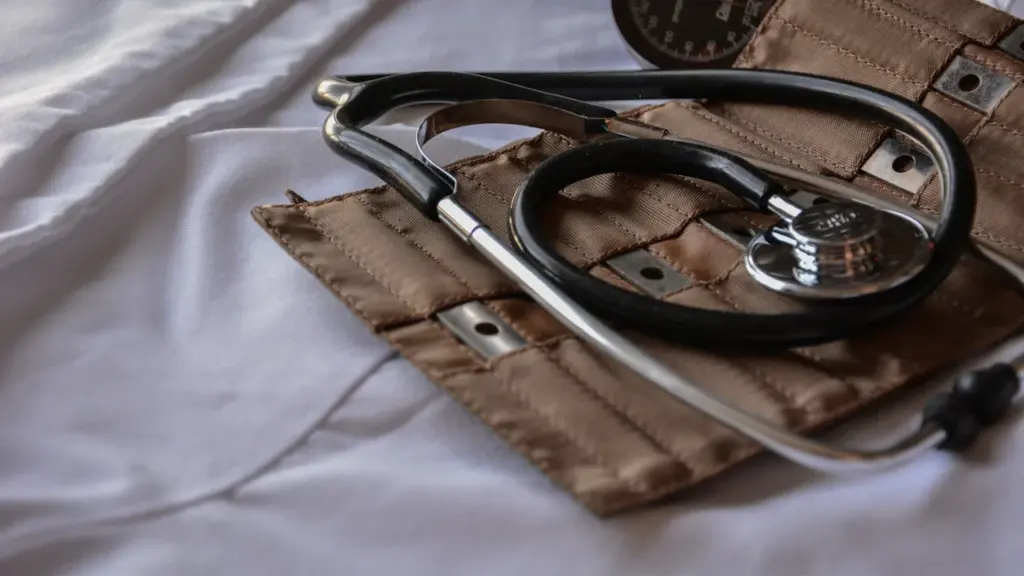 Gydytojo stetoskopas ant balto chalato, simbolizuojantis medicinos specialistų sugrįžimą į Lietuvą.
