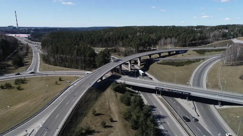 Daugiapakopė automobilių sankryža Vilniuje, simbolizuojanti Lietuvos kelių infrastruktūros pokyčius ir eismo sistemą.