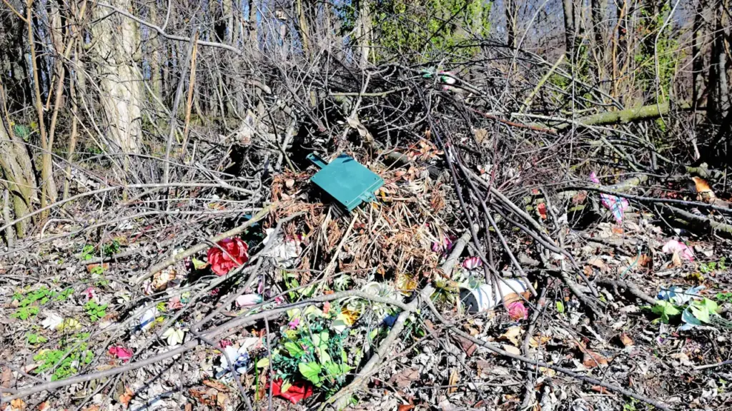 Išmestos atliekos ir dirbtinės gėlės paliktos miško pakraštyje šalia Vilniaus rajono.