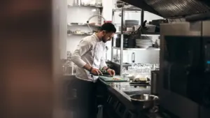 Šefas profesionalioje virtuvėje ruošia maistą gastronominio turizmo strategijos kūrimui ir plėtrai.