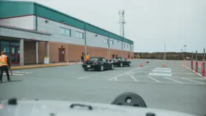Modernas pastatas su automobilių stovėjimo aikštele, kurioje organizuojami egzaminai ar praktinės užduotys.