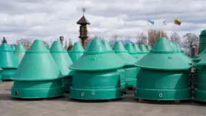 Daugybė žalių kūgio formos plastikinių elementų, sudėtų lauke ant asfaltuotos aikštelės.