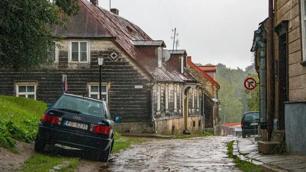 Istorinis namas su akmenimis grįsta gatve, primenantis Lietuvos tarpukario ir Sąjūdžio architektūrą.