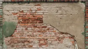 Sena raudonų plytų siena su nutrupėjusiu tinku, paruošta renovacijos darbams.
