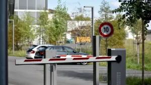 Automatizuotas užtvaras prie automobilių stovėjimo aikštelės su ribojimo ženklu.