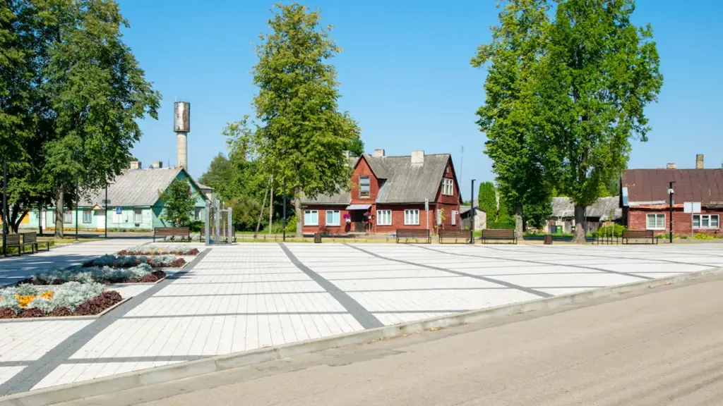 Vydenių seniūnijos administracijos pastatas ir atnaujinta aikštė Varėnos rajone šviečiant saulėje.