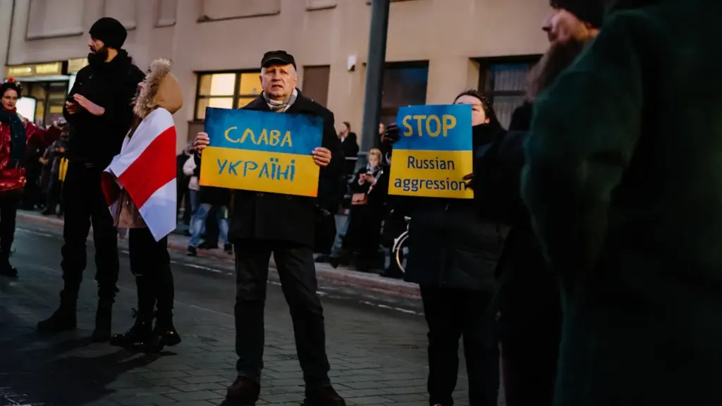 Žmonės su plakatais žygiuoja Vilniaus gatve solidarizuodamiesi su Ukraina svarbiame visuomeniniame renginyje.