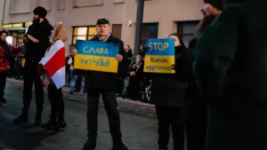 Žmonės su plakatais žygiuoja Vilniaus gatve solidarizuodamiesi su Ukraina svarbiame visuomeniniame renginyje.
